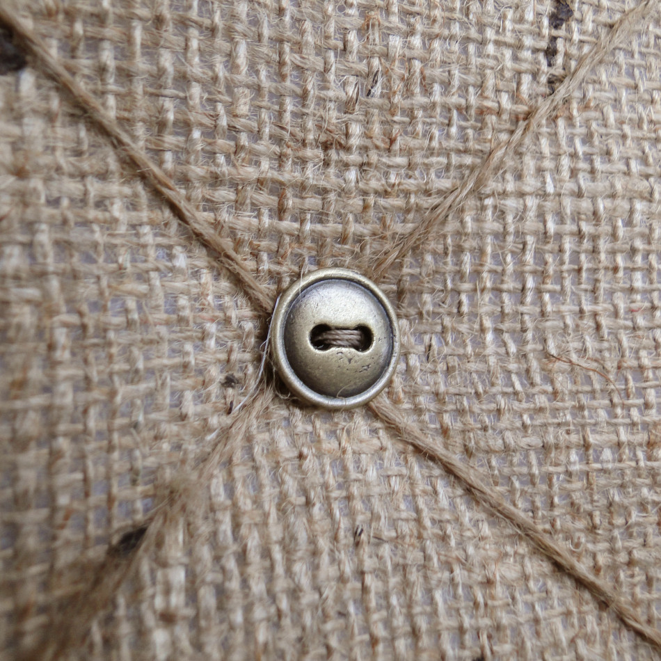 Close view of the natural hessian, crossed twine and antique brass button details